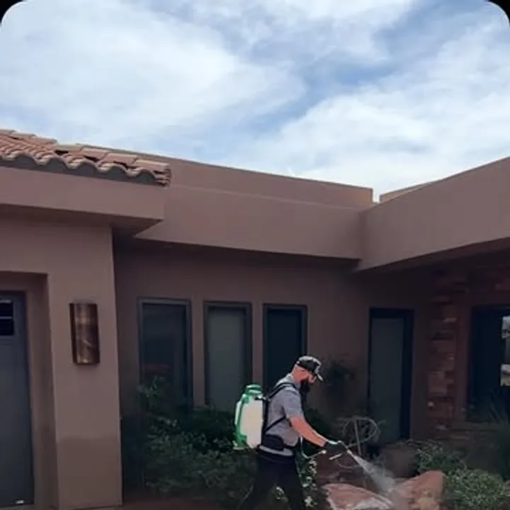 A Pallas Pest Control technician spraying a St. George home exterior